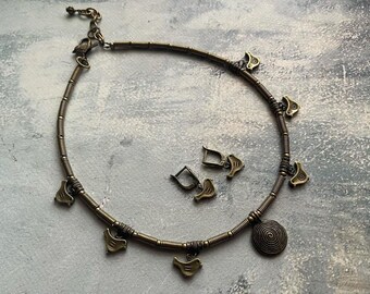 May include: A gold-toned necklace with a spiral charm and multiple bird charms. Matching earrings are also included.