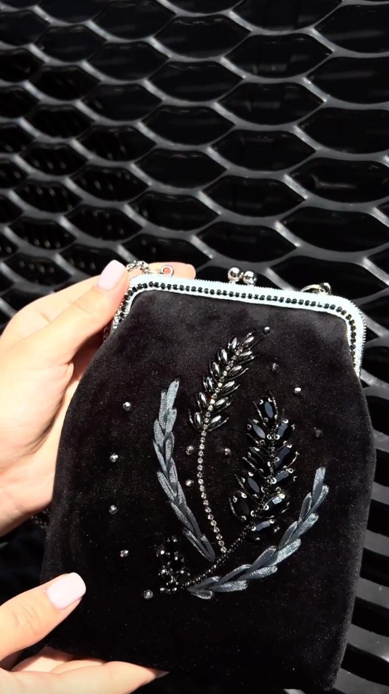 May include: A black velvet clutch bag with a floral design embroidered with black beads and sequins.