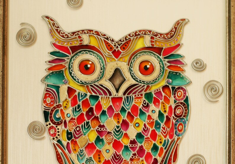 May include: A colorful stained glass owl with intricate details and a gold background. The owl's eyes are large and orange, and its feathers are a mix of red, green, yellow, and blue.