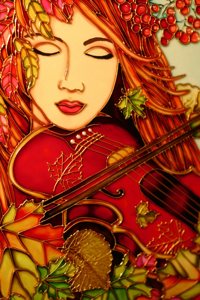 Pu&ograve; includere: Un'opera d'arte in vetro colorato che raffigura una donna con lunghi capelli rossi che suona il violino. Gli occhi della donna sono chiusi ed &egrave; circondata da foglie autunnali e bacche.