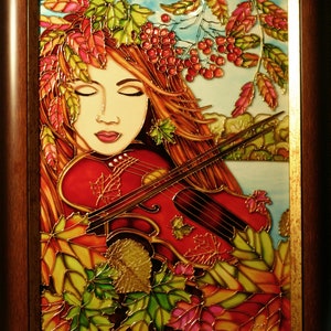 Pu&ograve; includere: Un'opera d'arte in vetro colorato che raffigura una donna con i capelli rossi che suona il violino. La donna &egrave; circondata da foglie autunnali in tonalit&agrave; di rosso, arancione, giallo e verde. Lo sfondo &egrave; un cielo azzurro chiaro con nuvole bianche.