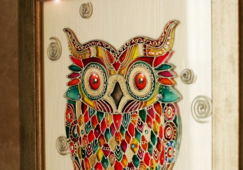 May include: A colorful stained glass owl with red, yellow, green, and blue glass pieces. The owl is framed in a wooden frame.