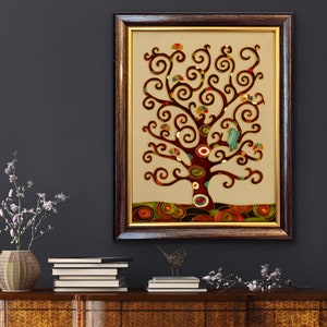 May include: A framed artwork featuring a stylized tree with brown branches and colorful leaves. The tree is set against a cream background with a brown border. The artwork is in a dark brown frame with a gold trim.