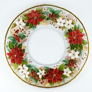 May include: A clear glass plate with a gold rim, decorated with red poinsettias, white flowers, green leaves, and red berries. The floral design is arranged around the plate's edge, creating a festive holiday theme. The plate has a diameter of approximately 10 inches.