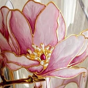 Peut inclure: Gros plan sur un vase en verre transparent avec un motif floral rose et blanc peint &agrave; la main. La fleur a des contours dor&eacute;s et un centre rouge. Le vase est probablement &agrave; des fins d&eacute;coratives.
