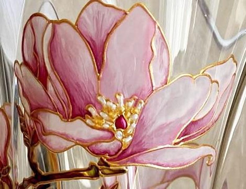 Peut inclure: Gros plan sur un vase en verre transparent avec un motif floral rose et blanc peint &agrave; la main. La fleur a des contours dor&eacute;s et un centre rouge. Le vase est probablement &agrave; des fins d&eacute;coratives.