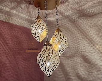 May include: A gold-toned chandelier with three ornate, teardrop-shaped light fixtures. Each fixture has a delicate, intricate pattern.