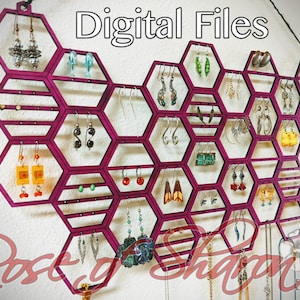 May include: A pink hexagonal earring holder with 20 slots for earrings. The holder is made of wood and has a modern design. The text "Digital Files" is printed at the top of the image.