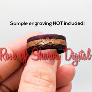 May include: A close-up of a wooden ring with a purple and brown wood grain pattern. The ring has a mountain scene engraved on it. The text "Sample engraving NOT included!" is visible at the top of the image.