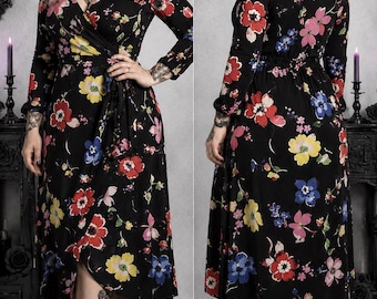 May include: A black midi-length wrap dress featuring long sleeves and a vibrant floral print with red, yellow, pink, and blue flowers. The dress has a V-neckline, a tie-waist closure, and a flowing skirt that falls below the knees in a classic silhouette.