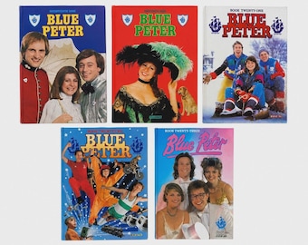 May include: Five hardcover Blue Peter annual books featuring photographic covers. The books are titled Seventeenth, Twentieth, Twenty-One, Twenty-Two, and Twenty-Three, displaying various presenters and themes including historical costumes, winter sports, and action scenes.