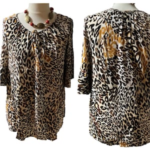 May include: A white, brown, and black leopard print blouse with a tie at the neckline. The blouse has 3/4 sleeves with a bell shape at the cuff.