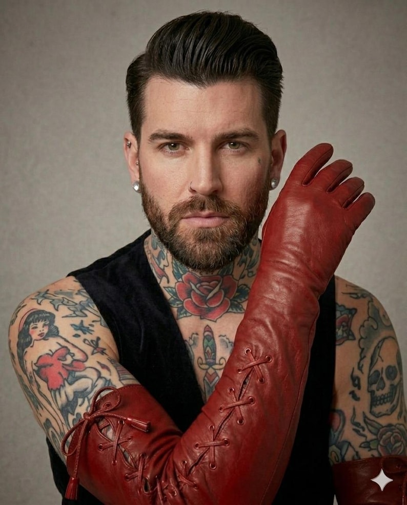 May include: A pair of long, deep red leather gloves featuring a lace-up design that extends from the wrist up the forearm. The gloves include thin matching red laces threaded through metal eyelets, creating a crisscross pattern along the length.