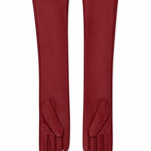 May include: A pair of long, deep red opera-length gloves crafted from a smooth, matte material. These gloves extend well past the wrist, featuring a sleek, seamless design with defined finger sections and a thumb placement on the inner side.