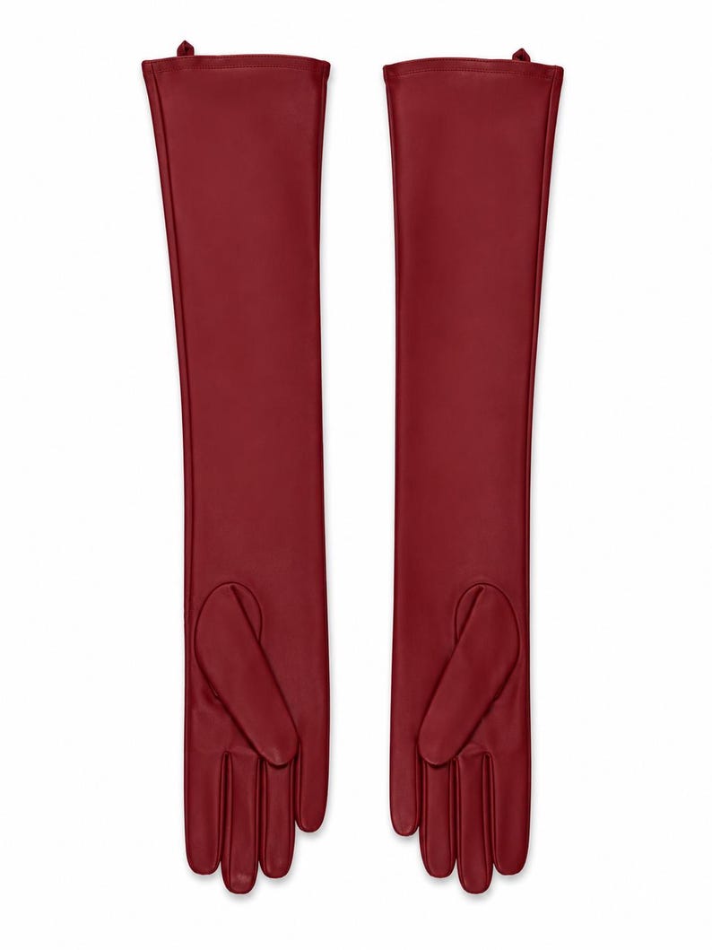 May include: A pair of long, deep red opera-length gloves crafted from a smooth, matte material. These gloves extend well past the wrist, featuring a sleek, seamless design with defined finger sections and a thumb placement on the inner side.