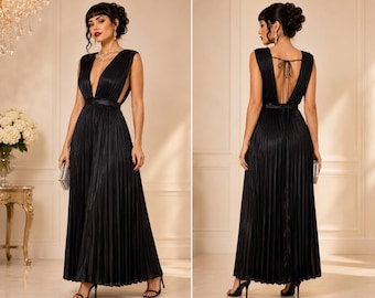 May include: A floor-length black pleated dress featuring a deep V-neckline, wide shoulder straps, and a satin waistband. The back of the dress includes a low-cut design with thin tie closures at the top, showcasing a full, flowing pleated skirt.