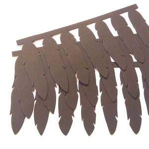 May include: A dark brown, decorative feather headdress, cut from a single sheet of material. The feathers are arranged in a layered pattern, attached to a horizontal band. The background is white.