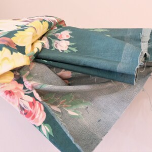 K&ouml;nnte beinhalten: Ein Stapel Stoff mit Blumenmustern in den Farben Rosa, Gelb und Gr&uuml;n. Der Stoff ist gefaltet und &uuml;bereinander gelegt, wobei die oberste Schicht ein dunkelgr&uuml;ner Stoff mit Blumenmuster ist.