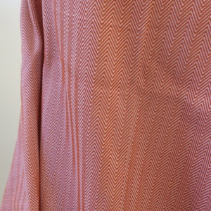 May include: A close-up of a soft, woven fabric with a herringbone pattern in shades of orange and white.