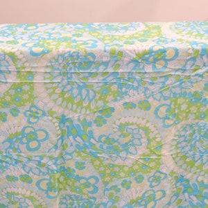 May include: A white fabric with a swirling blue and green floral pattern.