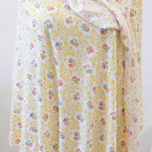 Puede incluir: Una tela amarilla con un patr&oacute;n floral blanco y rosa. La tela est&aacute; doblada y drapeada sobre un maniqu&iacute;.