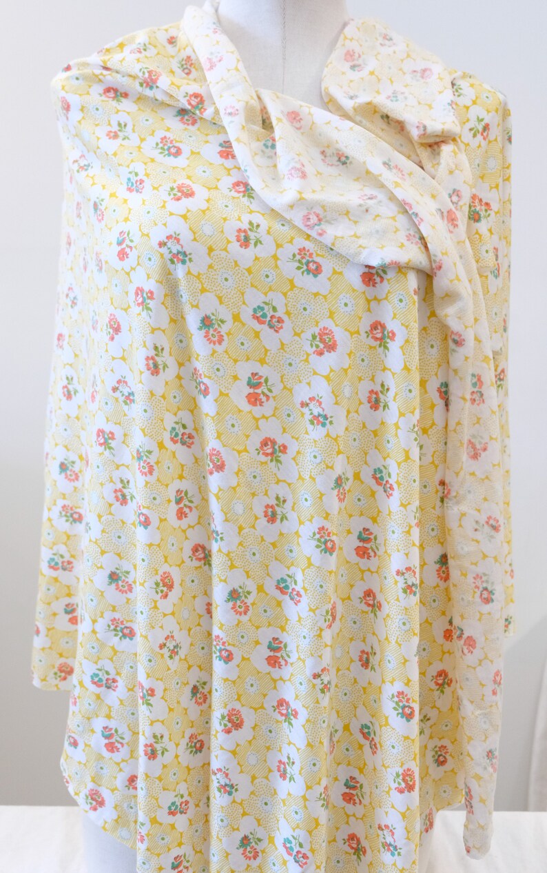 Puede incluir: Una tela amarilla con un patr&oacute;n floral blanco y rosa. La tela est&aacute; doblada y drapeada sobre un maniqu&iacute;.