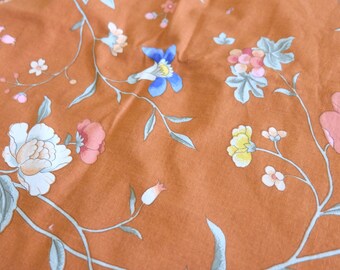 Könnte beinhalten: Nahaufnahme eines Stoffes mit Blumenmuster. Der Stoff ist hellbraun mit verschiedenen Blumen in den Farben Rosa, Blau, Gelb und Weiß. Die Blumen sind in einem sich wiederholenden Muster auf dem Stoff angeordnet.