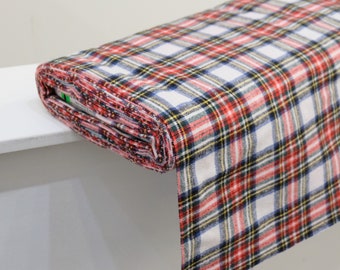 May include: A white fabric with red, blue, and yellow plaid pattern. The fabric is folded and rolled up.
