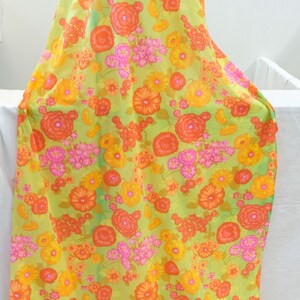 Puede incluir: Una tela verde con estampado floral con flores naranjas, amarillas y rosas. La tela es perfecta para proyectos de manualidades, acolchado o confecci&oacute;n de ropa.