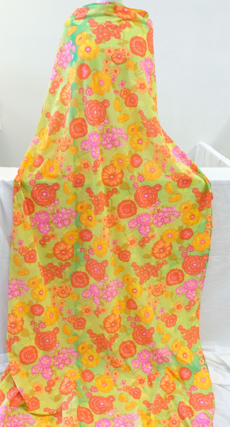 Puede incluir: Una tela verde con estampado floral con flores naranjas, amarillas y rosas. La tela es perfecta para proyectos de manualidades, acolchado o confecci&oacute;n de ropa.