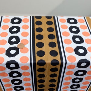 Pu&ograve; includere: Tessuto bianco con pois marroni, neri e arancioni e forme geometriche in un motivo a righe.