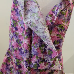 May include: A purple, pink and green floral print fabric with a white background. The fabric is draped over a white mannequin.