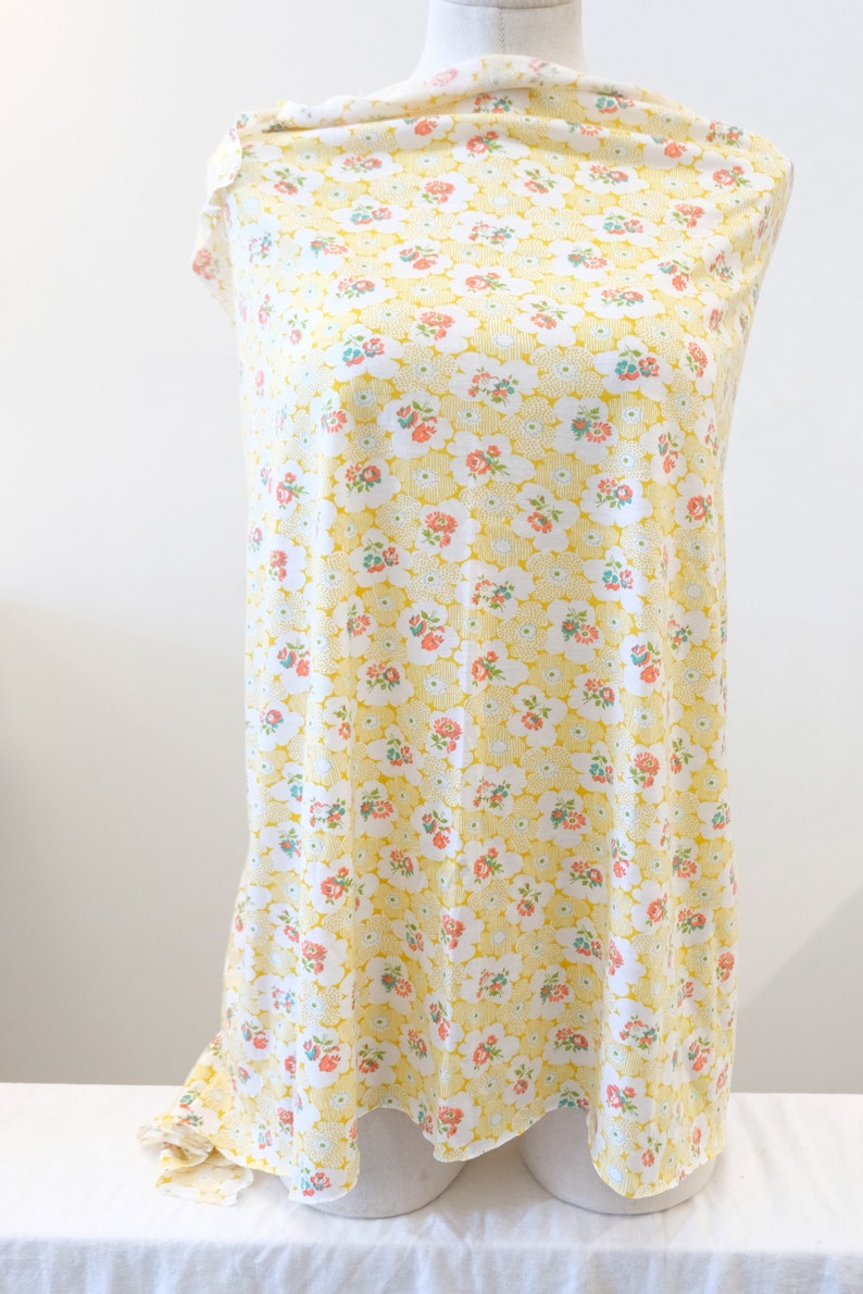 Puede incluir: Tela amarilla con fondo blanco y un peque&ntilde;o estampado floral. La tela est&aacute; drapeada sobre un maniqu&iacute; blanco.