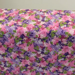 May include: A pink and purple floral fabric with a repeating pattern of flowers and leaves. The fabric is ideal for crafting projects, quilting, and home decor.