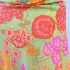 Puede incluir: Una tela verde con un patr&oacute;n floral con flores naranjas, rosas y rojas. La tela tiene una textura suave y transparente.