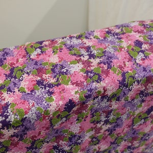 May include: Purple, pink and green floral fabric with a repeating pattern of stylised flowers.