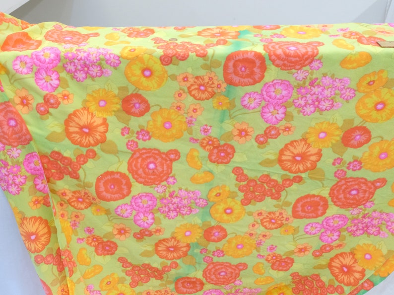 Puede incluir: Una tela verde con un patr&oacute;n floral con flores naranjas, amarillas y rosas. La tela tiene un aspecto vintage y ser&iacute;a ideal para proyectos de manualidades.