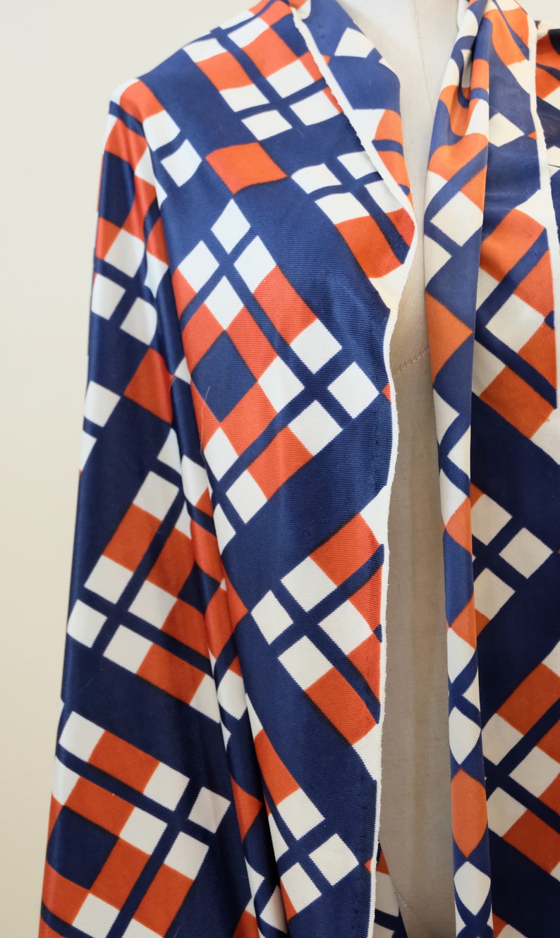 May include: A long-sleeved robe with a geometric pattern in shades of blue, white, and orange. The robe has a shawl collar and a tie closure.