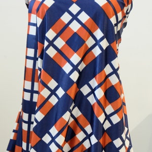 May include: A blue, white, and orange geometric patterned fabric. The fabric has a diamond pattern with a white background and blue and orange squares.