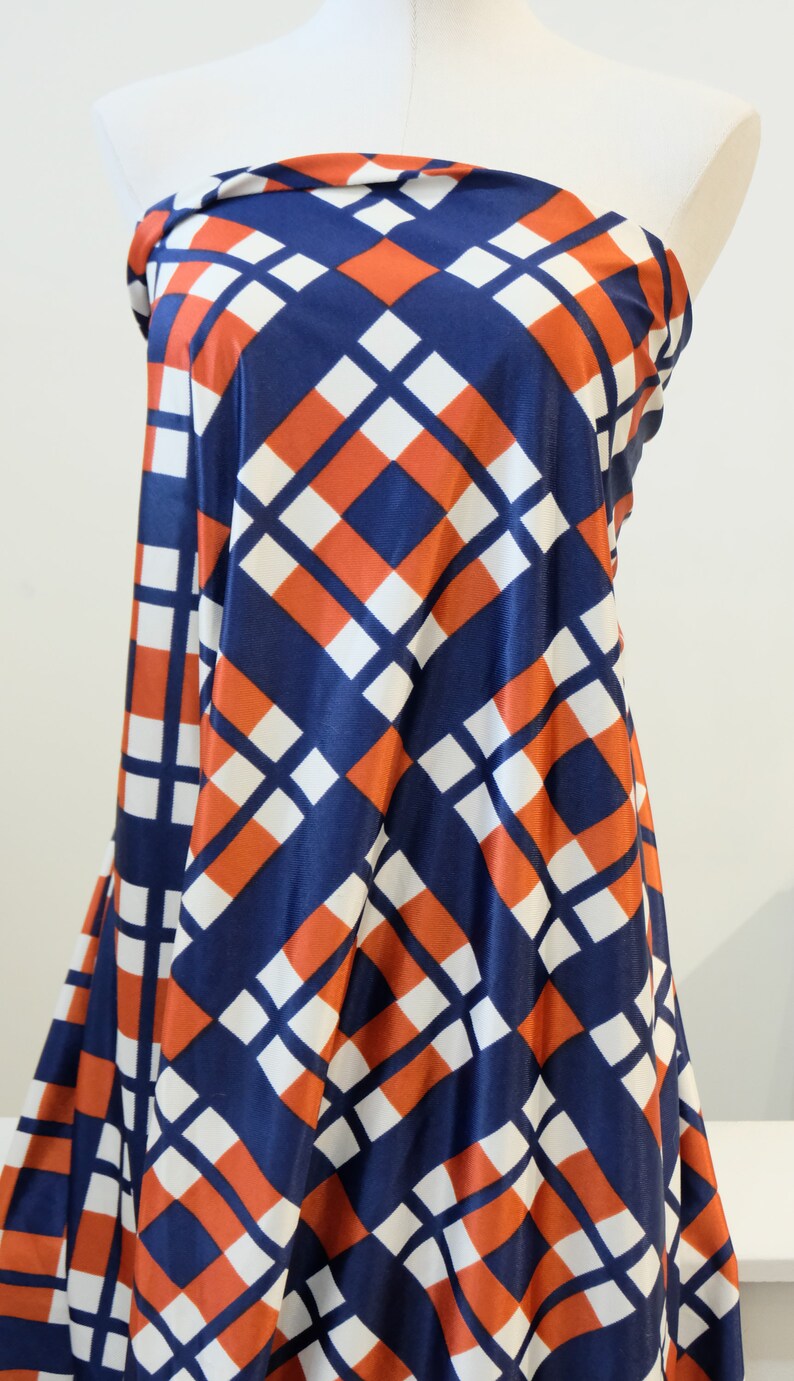 May include: A blue, white, and orange geometric patterned fabric. The fabric has a diamond pattern with a white background and blue and orange squares.