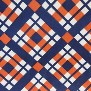 May include: A repeating geometric pattern of orange, white, and navy blue squares. The squares are arranged in a diagonal pattern, creating a checkered effect.