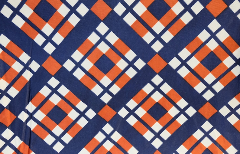 May include: A repeating geometric pattern of orange, white, and navy blue squares. The squares are arranged in a diagonal pattern, creating a checkered effect.