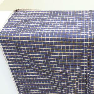 May include: A navy blue fabric with a yellow plaid pattern. The fabric is folded and displayed on a white surface.