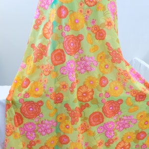 Puede incluir: Tela verde con estampado floral con grandes flores naranjas, amarillas y rosas. La tela tiene un aspecto vintage.