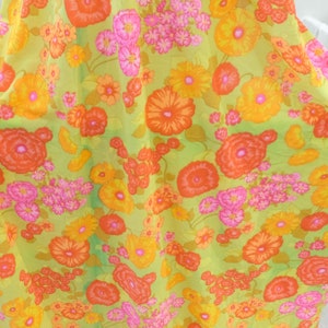 Puede incluir: Una tela verde con un patr&oacute;n floral con flores naranjas, rosas y amarillas. La tela tiene un aspecto vintage y ser&iacute;a perfecta para una variedad de proyectos de costura.