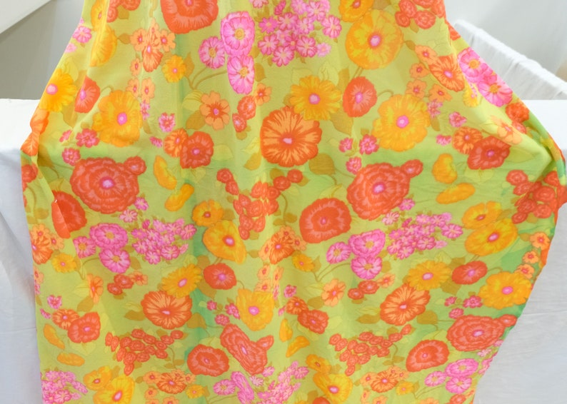 Puede incluir: Una tela verde con un patr&oacute;n floral con flores naranjas, rosas y amarillas. La tela tiene un aspecto vintage y ser&iacute;a perfecta para una variedad de proyectos de costura.