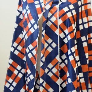 May include: A blue, white, and orange geometric patterned fabric. The fabric has a diagonal pattern of squares and rectangles.