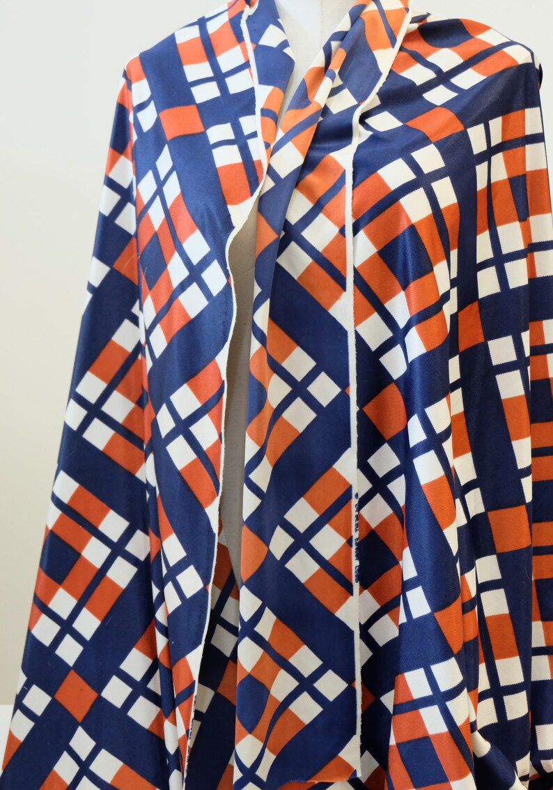 May include: A blue, white, and orange geometric patterned fabric. The fabric has a diagonal pattern of squares and rectangles.