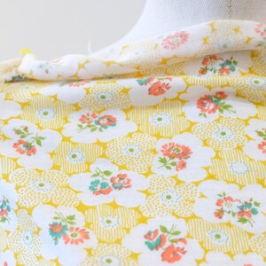 Puede incluir: Tela blanca con fondo amarillo y un patr&oacute;n floral de peque&ntilde;as flores rosas, rojas y azules. La tela tiene una textura sutil.