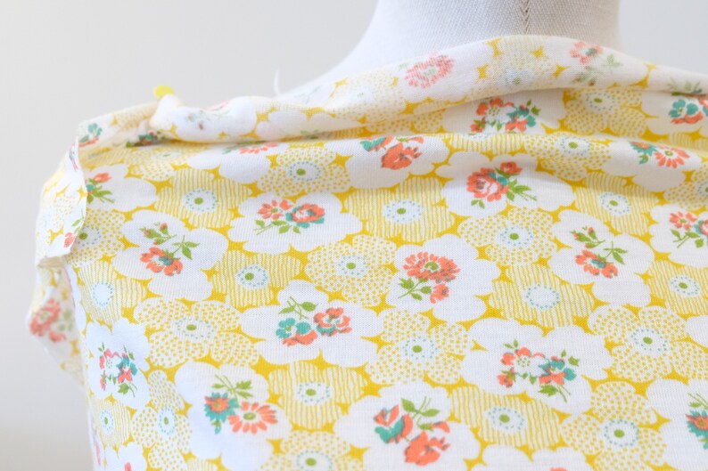 Puede incluir: Tela blanca con fondo amarillo y un patr&oacute;n floral de peque&ntilde;as flores rosas, rojas y azules. La tela tiene una textura sutil.